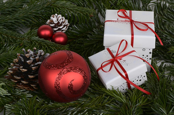 Geschenke und eine Christbaumkugel liegen auf Grünzeug