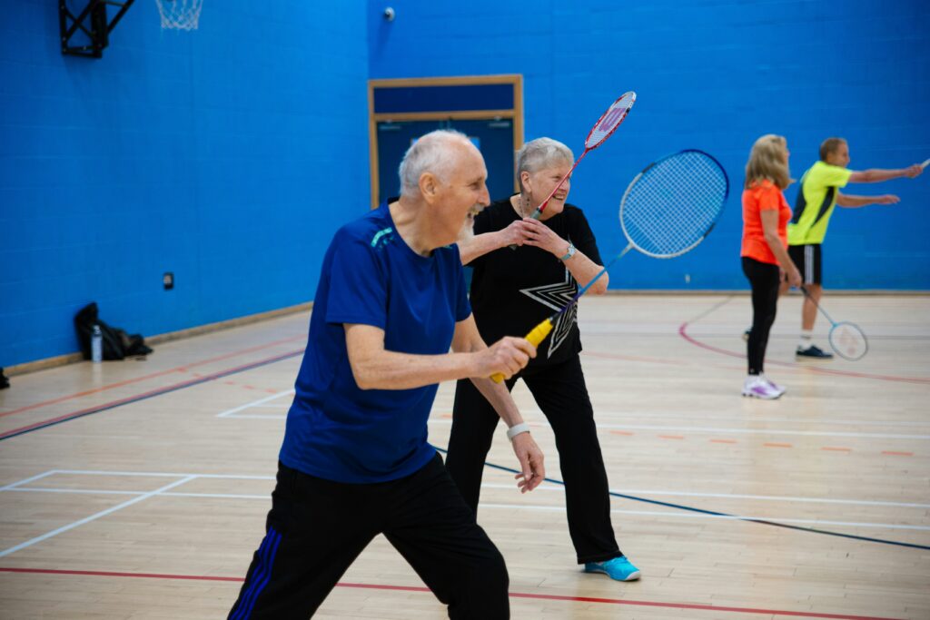 Senioren spielen Badminton in einer Turnhalle