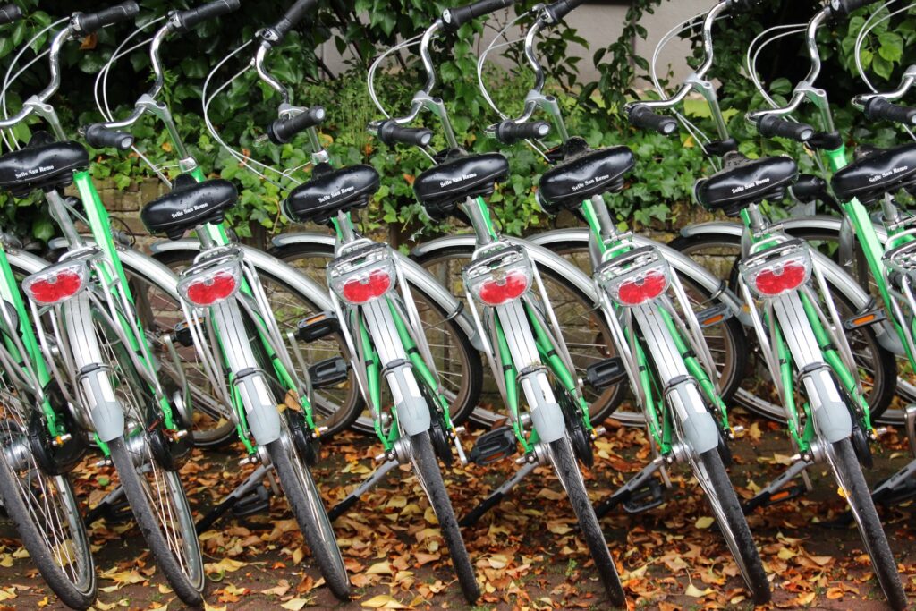 Eine Reihe grüner Mieträder vor einer Mauer.
