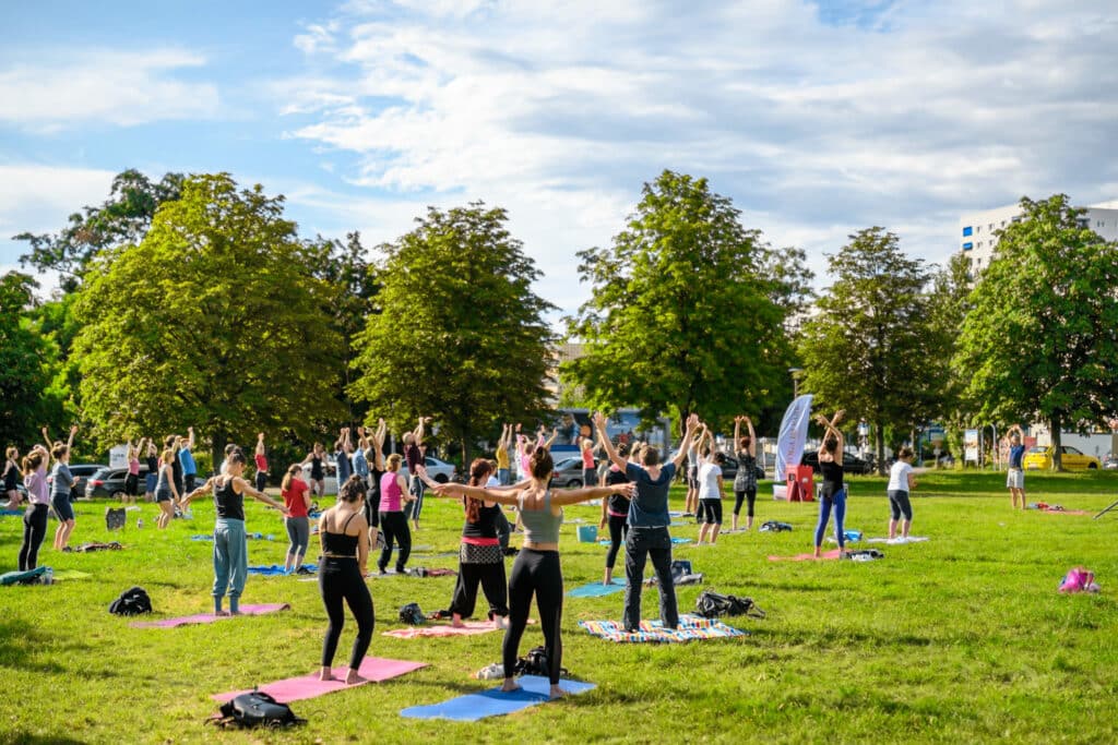 Besucher:innen machen gemeinsam Yoga im Park.