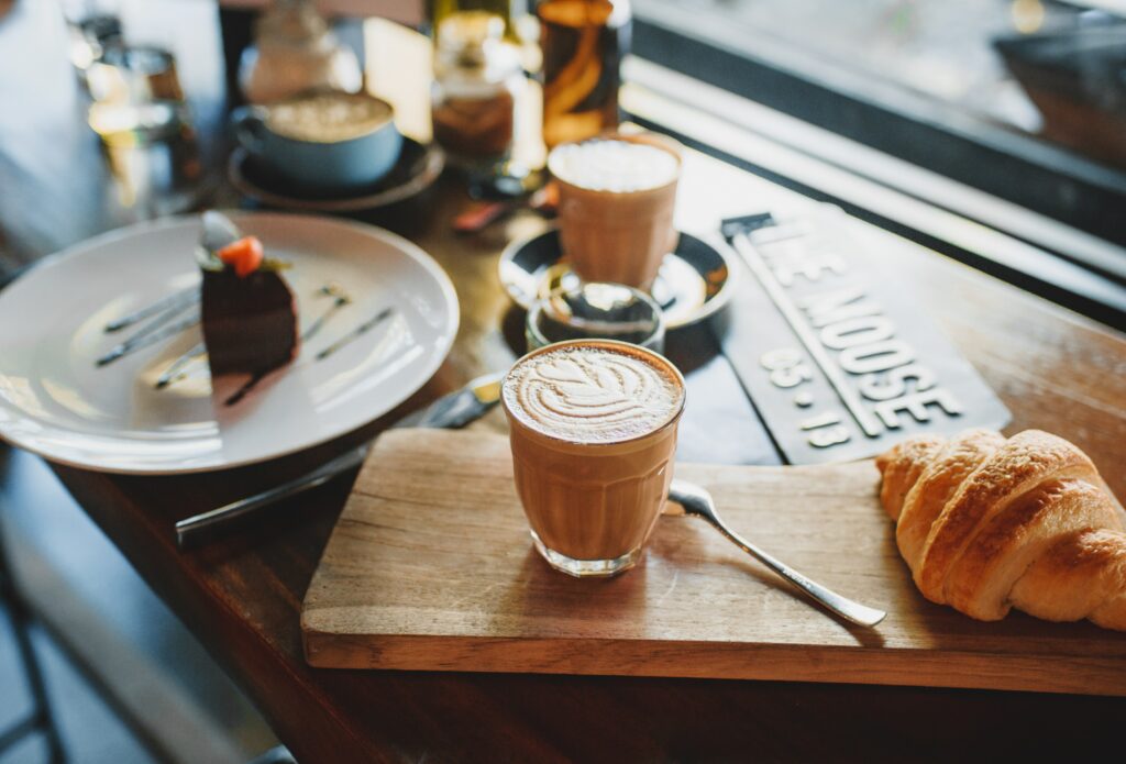 Ein Croissant, Tassen Kaffee und ein Stück Schokoladenkuchen.
