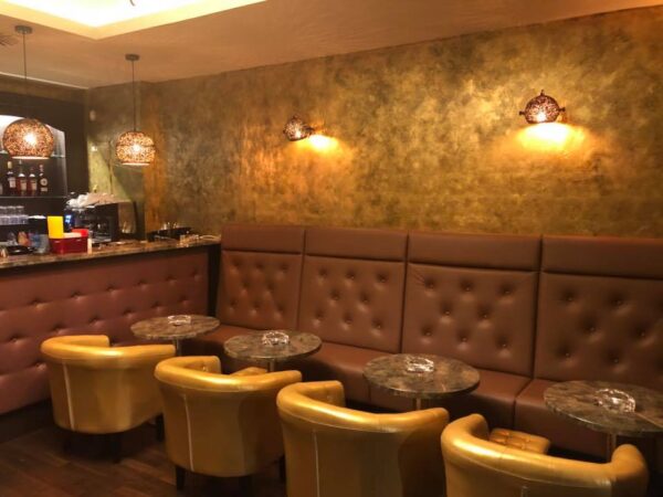 Braune Ledercouches und goldene Sessel in Miris Bar