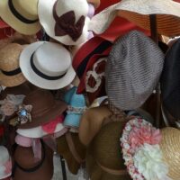 Viele bunte Hüte und Kopfbedeckungen hängen an Hutständern