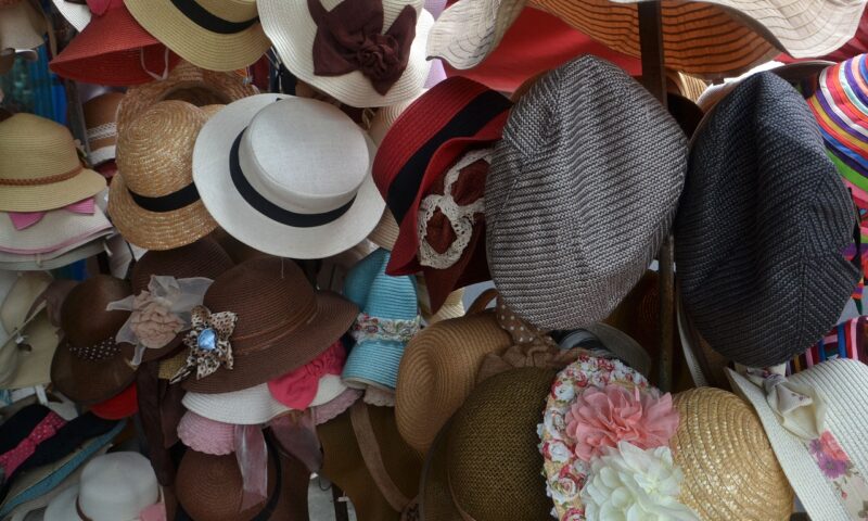 Viele bunte Hüte und Kopfbedeckungen hängen an Hutständern