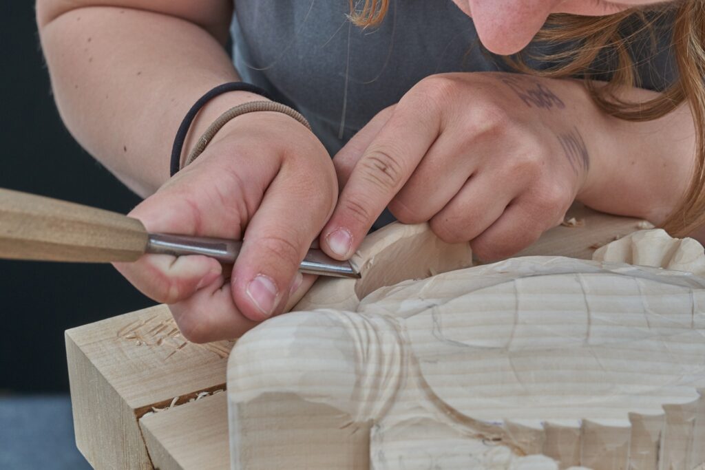 Eine Frau bearbeitet eine Holzfigur