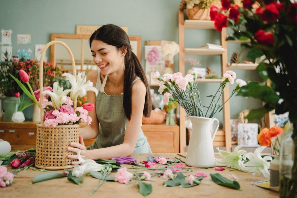 Eine lachende Frau stellt ein Blumengesteck her