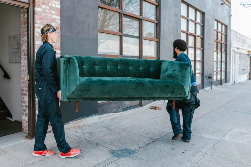 Möbelpacker tragen ein grünes Sofa