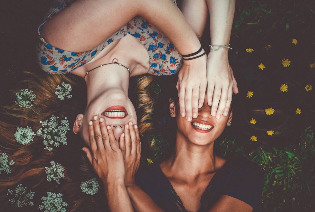 Zwei lachende Frauen auf einer Blumenwiese