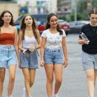 Vier weiblich gelesene Jugendliche laufen eine Straße entlang