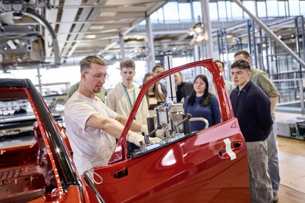 Besucher in der Gläsernen Manufaktur schauen sich ein rotes Auto an