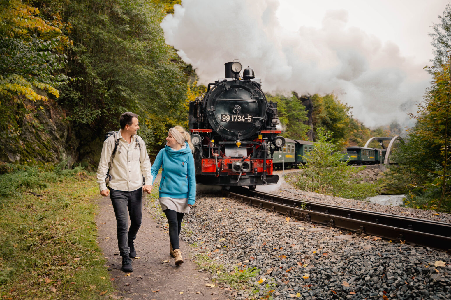 Wanderndes Pärchen im Weißeritztal mit dampfender Weißeritztalbahn im Hintergrund