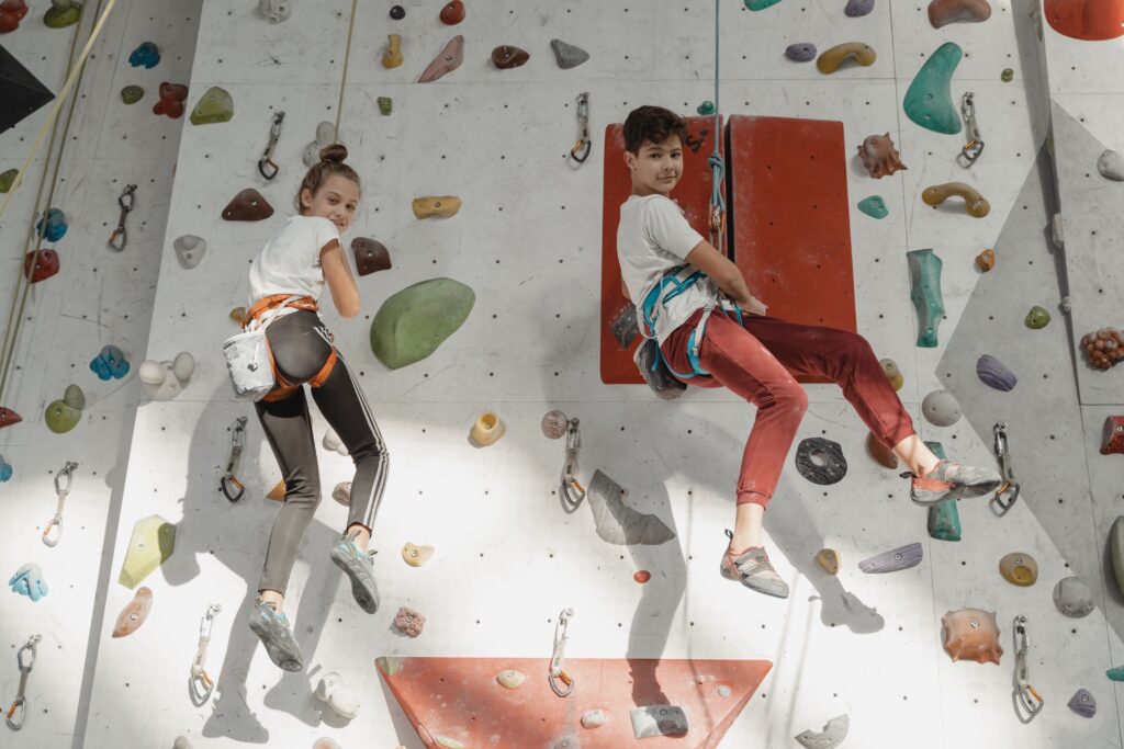 Kinder in Klettergurten an einer Kletterwand